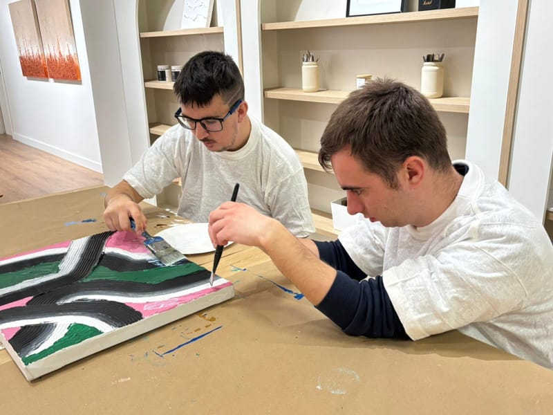 Participants creant art inclusiu amb textures en un taller de pintura