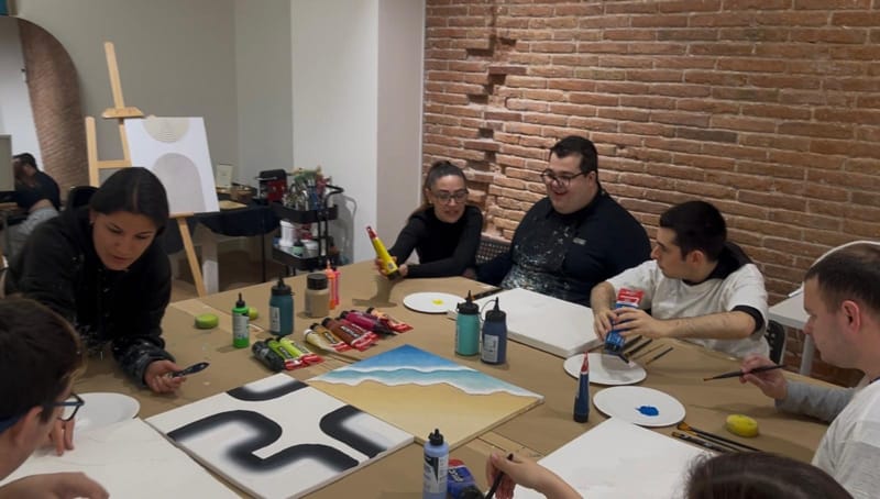 Participants creant art inclusiu amb textures en un taller de pintura
